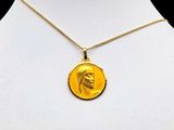 the necklace has a gold coin with a picture of a man ' s face on it
