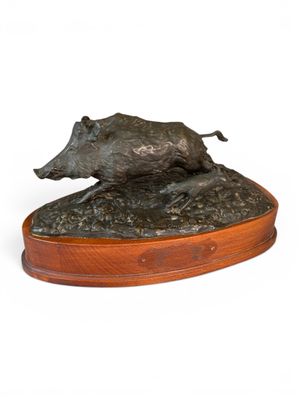 sculpture en bronze représentant un sanglier, posée sur un socle en bois, sur fond blanc