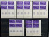 Les timbres violets et blancs sont posés sur une étagère noire devant un mur blanc.