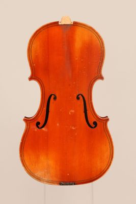 un vieux violon posé sur un chevalet devant un fond blanc