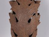 a rusted metal vase with holes in it