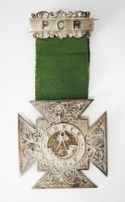 une vieille médaille en argent ornée d'un ruban vert sur fond blanc