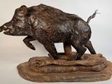 statue d'un sanglier posée sur un socle en bois, sur fond blanc