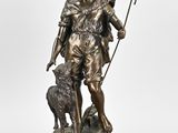 a bronze statue of a man with a dog and a stick