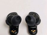 pair of black ear buds sitting on top of each other on a white surface