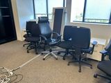quatre chaises de bureau noires dans une pièce dotée d'une grande fenêtre