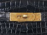 an image of a close up of a black purse with a gold buckle