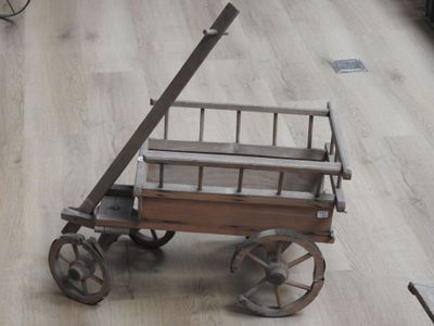 un petit chariot en bois muni d'une poignée en métal et d'un plancher en bois