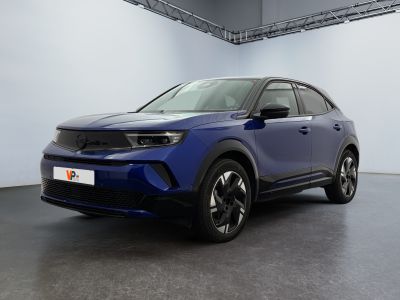 a blue car is parked in a large room with a white wall