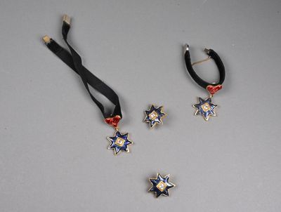 trois bijoux posés sur une table, entourés d'un ruban