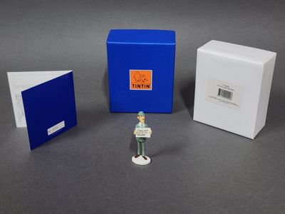 une petite figurine représentant un homme debout devant une boîte