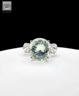 un gros plan d'une bague en diamant verte posée sur une assiette blanche