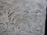 a stone relief of a man on a horse drawn carriage