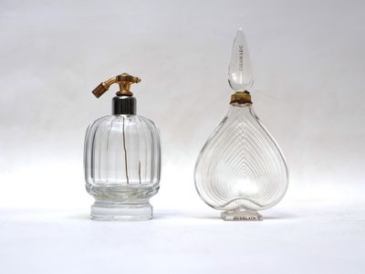 une paire de flacons de parfum en verre transparent rehaussés de touches dorées sur fond blanc