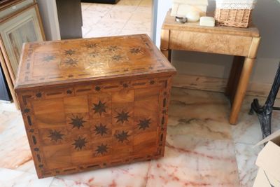 a wooden box sitting on a marble floor next to a table