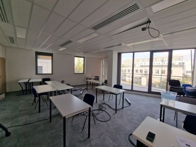 une pièce équipée de tables et de chaises, d'où l'on a une vue sur la ville