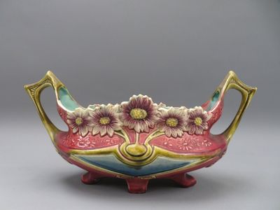 un vase coloré orné de fleurs, posé sur un socle