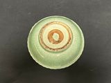 a green bowl with a brown rim sitting on a table