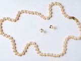 un collier de perles et une paire de boucles d'oreilles posés sur un fond blanc