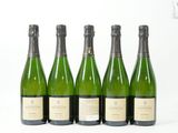 quatre bouteilles de vin sont alignées sur une surface blanche