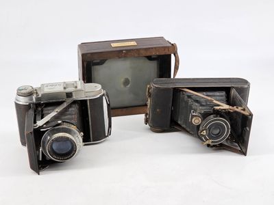 three old cameras sitting next to each other on a white surface