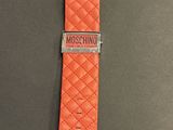 an orange watch strap with a metal clasp on a gray surface