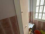 a cabinet in the corner of a bathroom with a bucket on the floor next to it