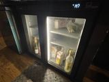 two refrigerators with drinks inside of them on the floor
