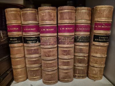 several old books stacked on top of each other on a shelf