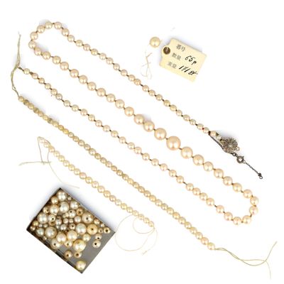 trois colliers de perles et une boîte de perles posés sur une surface blanche