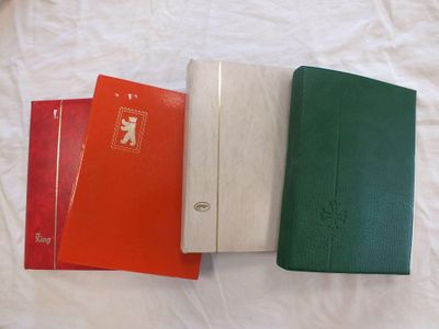 trois cahiers de couleurs différentes sont alignés sur un lit