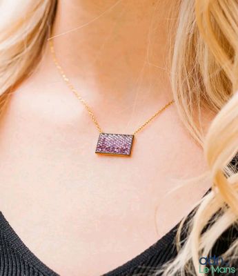 a woman wearing a necklace with a purple druzy stone on it