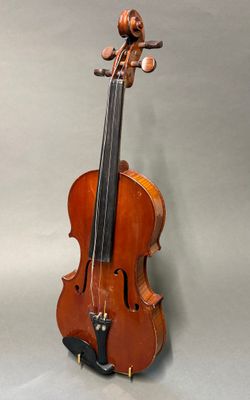 un vieux violon posé sur une table, devant un fond gris