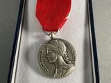 silver medal with a red ribbon in a box on a table