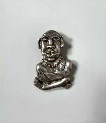 an image of a silver figurine of a man with his arms crossed