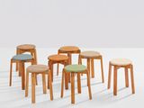 several wooden stools with different colored cushions in a white room