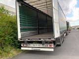 a truck that is driving down the road with a trailer behind it