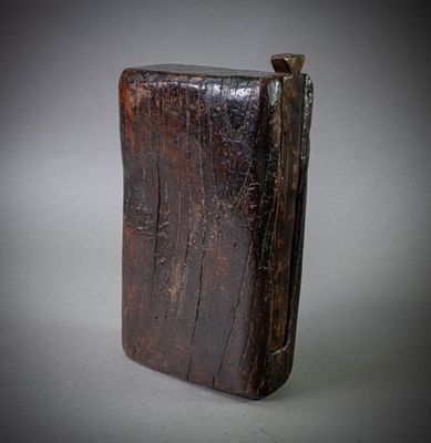 an old wooden book sitting on top of a gray surface