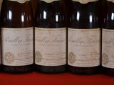 six bottles of wine are lined up on a red table