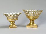two gold vases sitting next to each other on a white surface