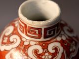 a red and white vase sitting on a table