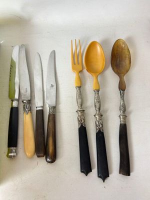 a lot of different types of knives and spoons on the table