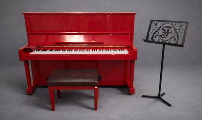 un piano rouge posé à côté d'un pupitre