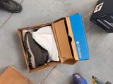 a box of shoes on the ground next to a pair of shoes