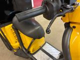 a close up of a yellow scooter parked in a garage