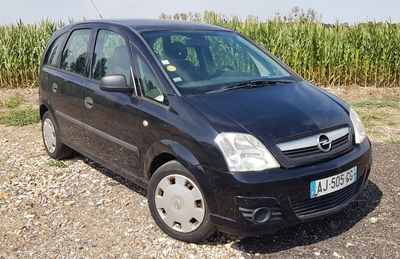 a picture of a small black car parked in a gravel lot