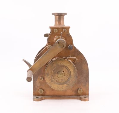 une vieille machine plaquée laiton posée sur une surface blanche, avec un fond blanc