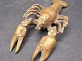 deux homards en laiton posés sur une surface noire, sur fond noir