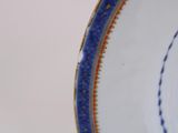 underside view of a blue and white plate with a gold border