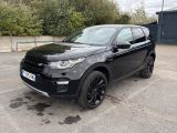 une Land Rover noire garée sur un parking, avec des arbres en arrière-plan